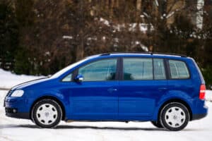 Ein blauer VW Touran in einer verschneiten Landschaft.