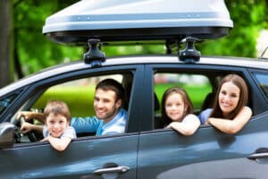 Eine glückliche junge Familie mit zwei Kindern im Auto.